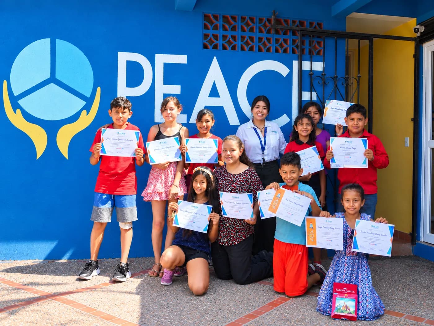 Estudiantes de PEACE Punta de Mita mostrando con orgullo sus reconocimientos frente al mural de PEACE